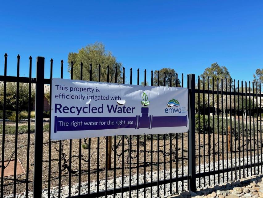 A sign on a fence promoting the use of recycled water.