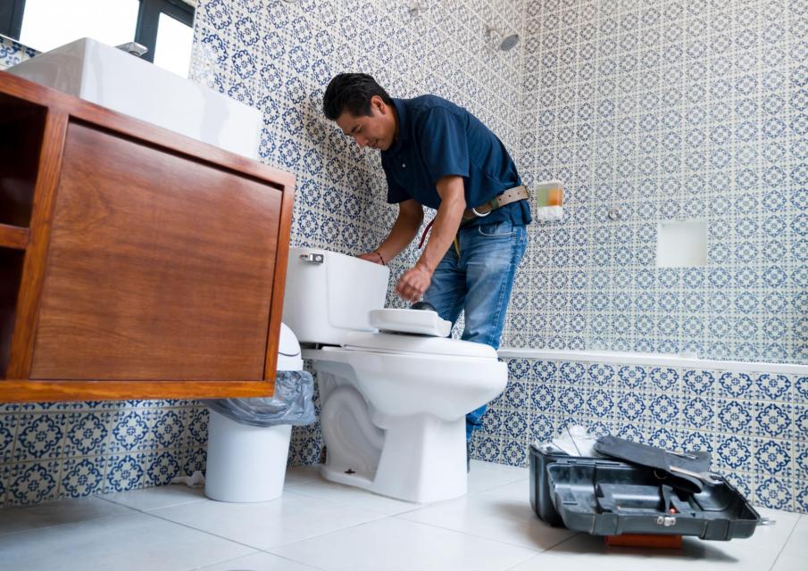 A plumber installing a toilet. 